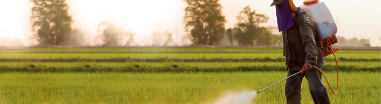 Farmer in Protective Clothing Working with a Roundup Sprayer