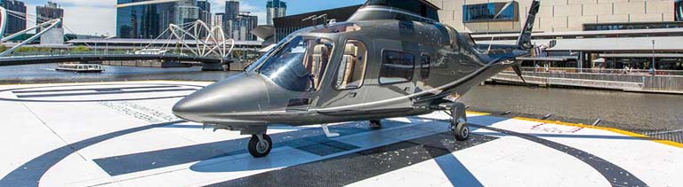 Black helicopter parked above a tall building